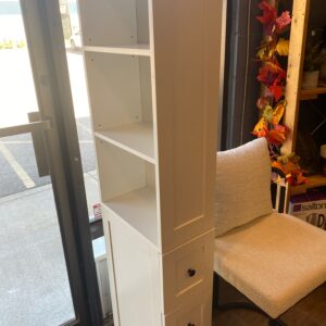 White narrow cabinet with three drawers, three shelves. 67”H, 9”W, 16”D